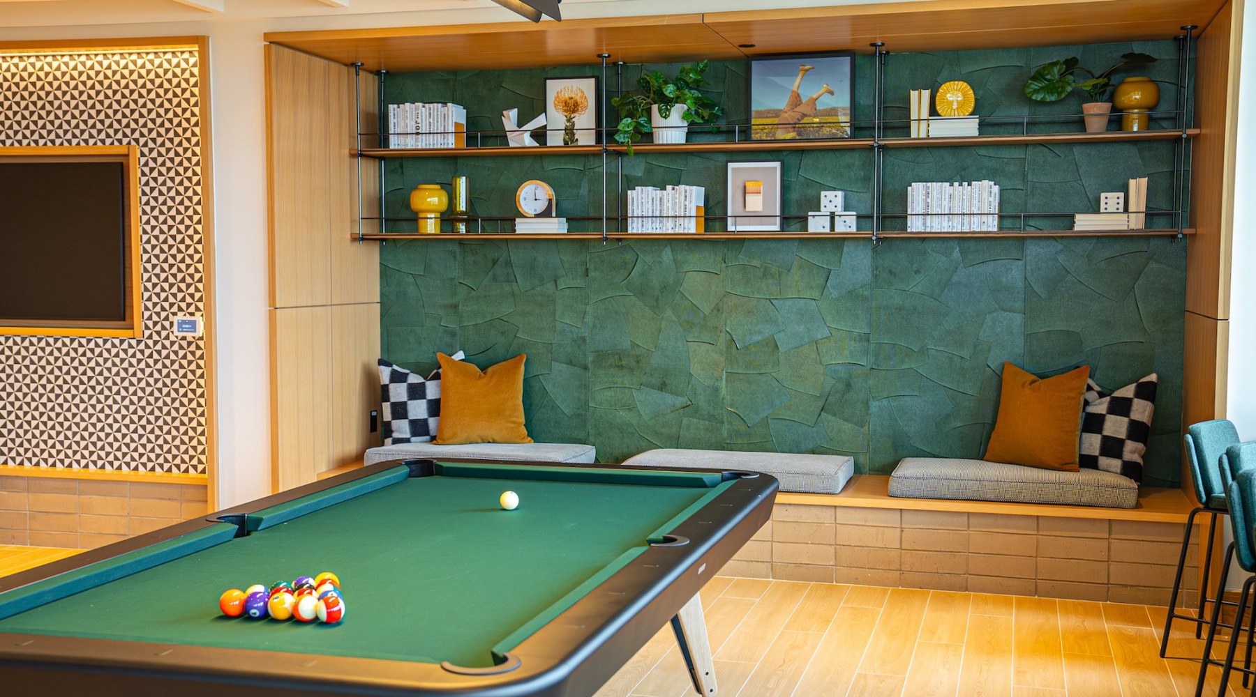 a pool table in a room with seating and shelving with different items on it